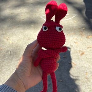 hand knitted red long legged bunny doll, soft cotton yarn, quirky angry expression, safe cozy companion, meaningful childhood keepsake
